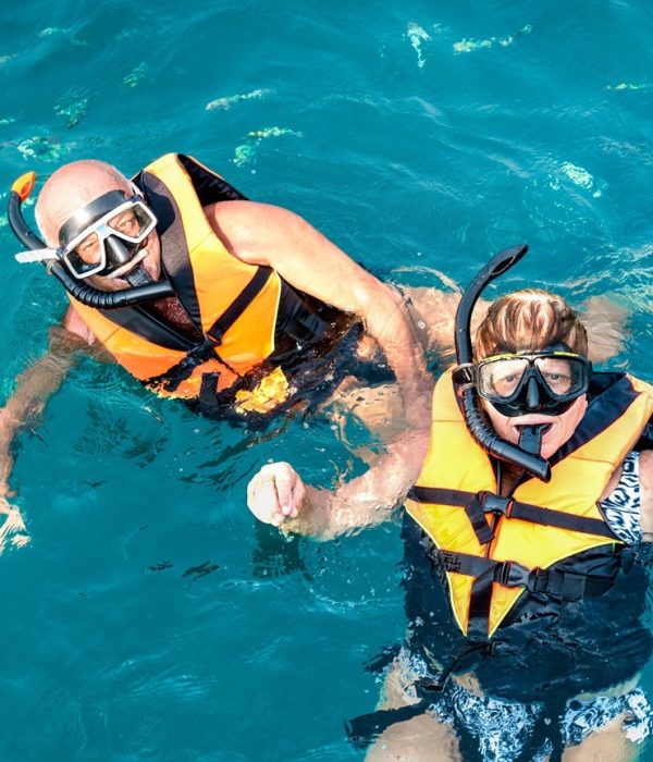 Senior couple posing for travel photo at snorkeling excursion in south east Asia during boat trip in exotic scenarios - Active retired elderly and fun concept around the world - Azure vivid filter